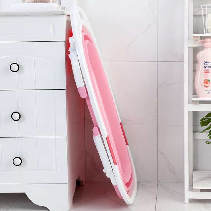 Pink and white folding chair against a white cabinet with a tiled wall background.
