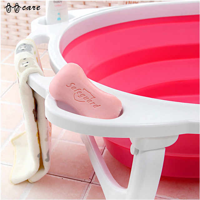 Pink inflatable bathtub with a white seat and a pink soap bar on a tiled floor.