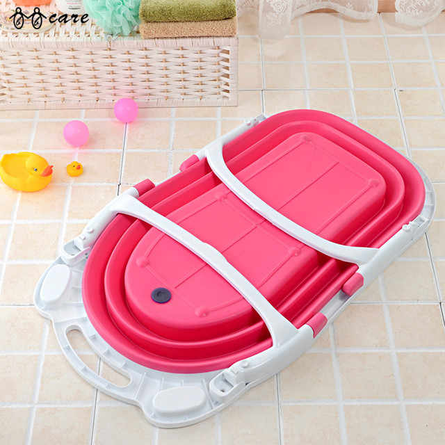 Pink and white collapsible bathtub on a tiled floor with toys in the background
