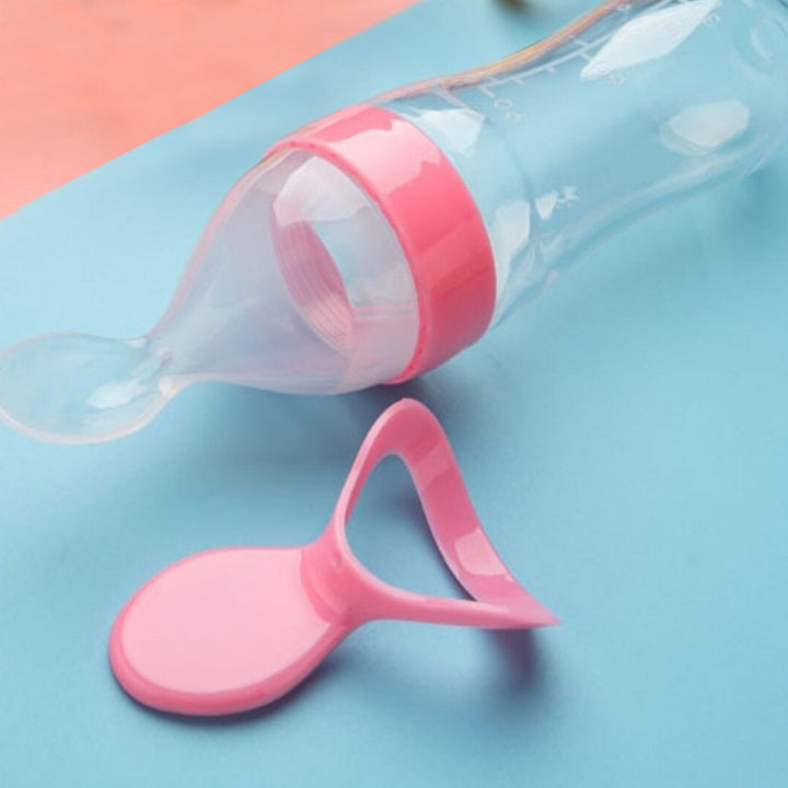 Pink baby bottle and spoon set on a blue and pink background