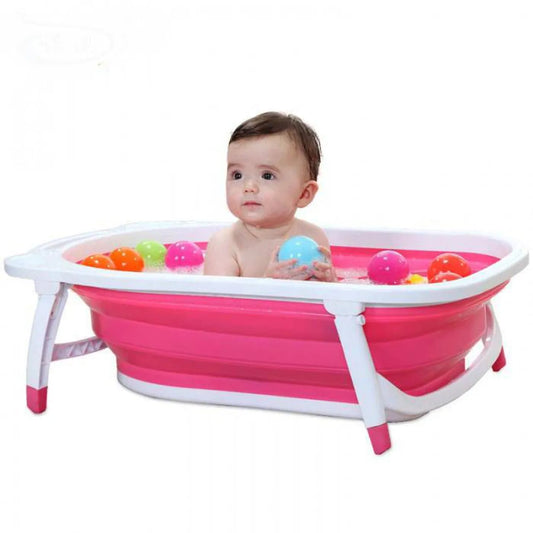 Baby playing with colorful balls in a pink inflatable bathtub on a white background